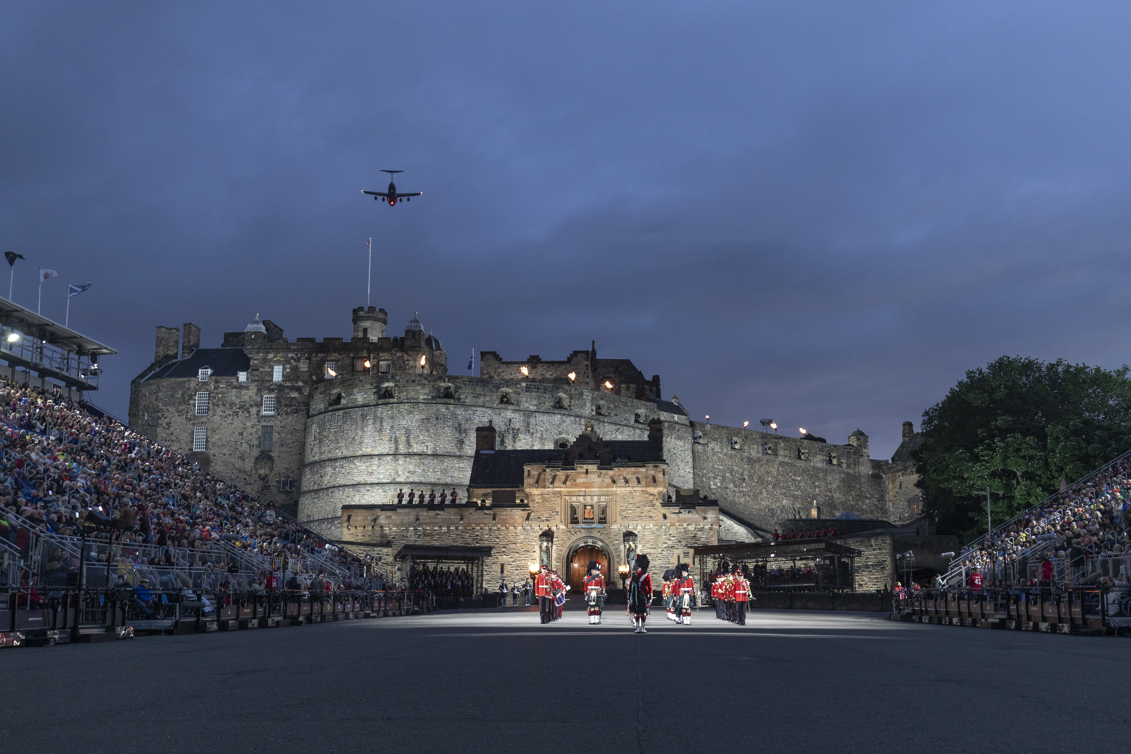 Image shows musicians outside Edinburgh Castle, with crowds and a flypast. 